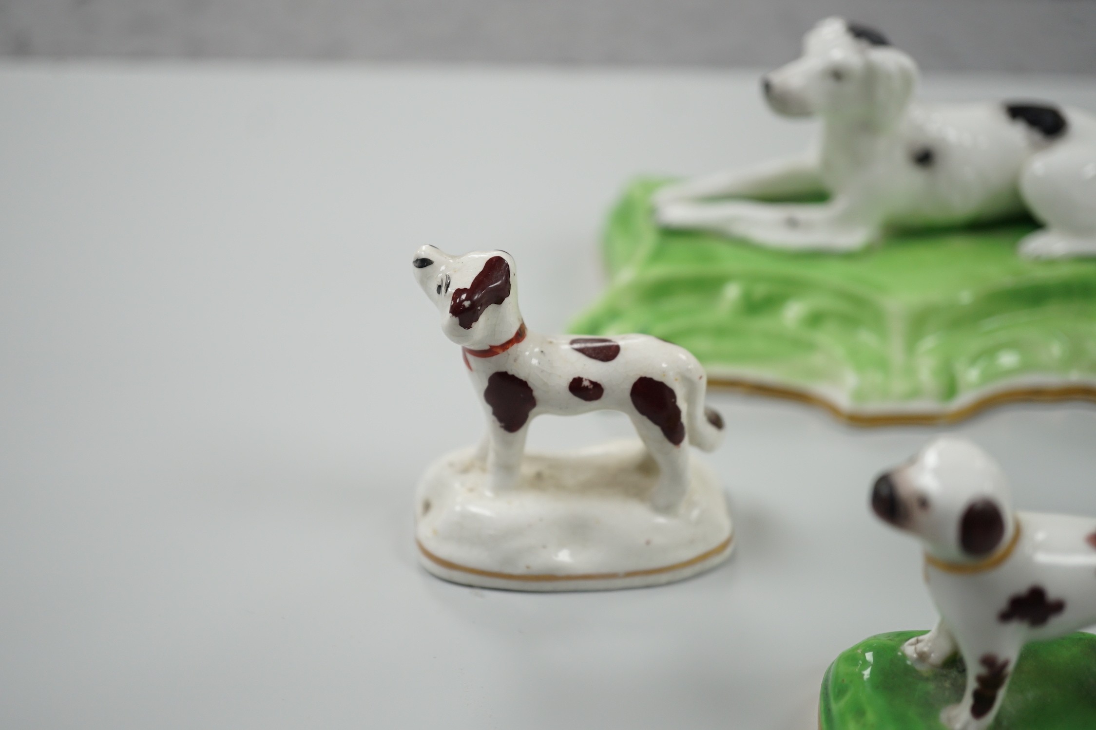 Three toy Staffordshire models of standing terriers; two with brown spots and the other black spots, together with a small Staffordshire model of a recumbent black and white setter on modelled base. c.1830-50, Largest 13